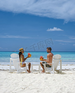 一对男女在海滩上喝椰子饮料，普拉兰塞舌尔热带岛屿，有海滩和棕榈树，安斯沃尔伯特塞舌尔海滩