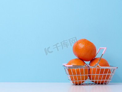 蓝色背景微型金属购物车中的成熟柑橘，柑橘涨价概念