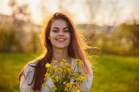 红发摄影照片_一位红发女子拿着一束黄色鲜花对着镜头快乐微笑的特写肖像