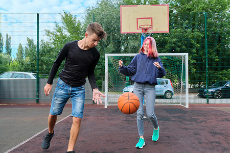 青少年男孩和女孩在户外篮球场打街头篮球