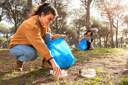 快乐的年轻白人女性活动家捡起塑料垃圾来清理森林。