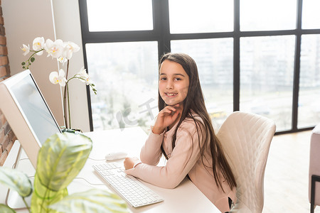 微笑的白人小女孩使用笔记本电脑与老师进行远程视频通话，快乐的小孩与导师挥手致意，在电脑上在线学习，在家上学的概念