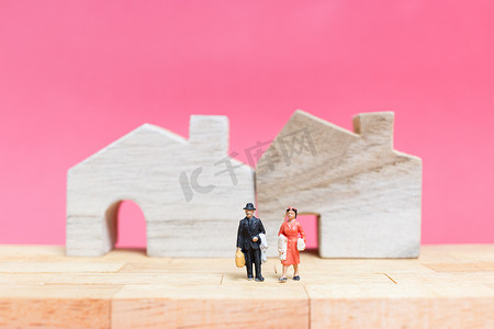 粉红色的房子摄影照片_夫妇与粉红色背景的房子，