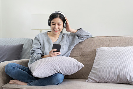 亚洲女人用手机和耳机听音乐。