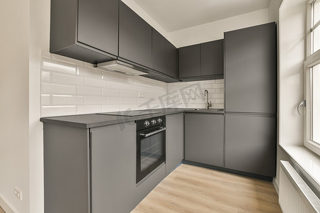 灰色橱柜摄影照片_厨房配有灰色橱柜、炉灶和水槽