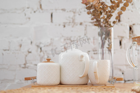 茶白套装在白色砖墙背景的木托盘上。