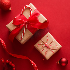红色背景礼物礼盒摄影照片_圣诞礼物、节礼日和传统节日礼物平躺，红色背景的经典圣诞礼盒，包装有节日装饰品和节日平躺装饰的礼物