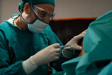 外科医生在手术前用无菌注射器给病人注射麻醉剂。