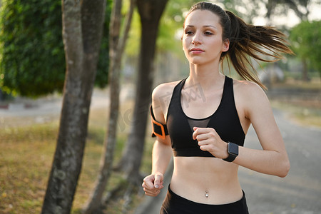 锻炼女性摄影照片_穿着运动服在夏季公园跑步的活跃运动白人女性的照片。