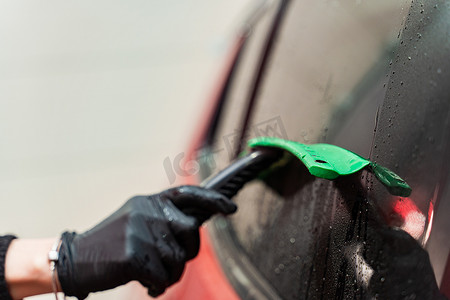 洗车玻璃摄影照片_洗车后用橡皮刮刀清除玻璃上的残留水。