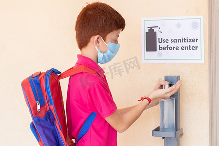 重新开张摄影照片_戴着医用口罩的孩子在进入教室前使用洗手液 — 回到学校或学校重新开放的概念以及冠状病毒或 covid-19 安全措施。