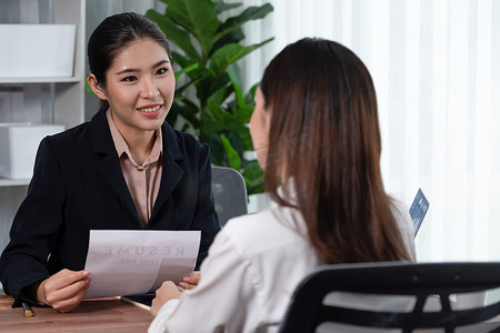 两名亚洲女性在办公室进行求职面试。