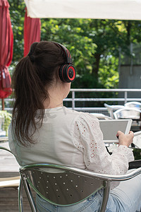 悲伤的女孩在咖啡馆的桌子上听平板电脑上的音乐