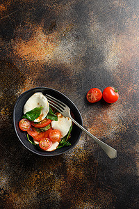 番茄、罗勒、马苏里拉奶酪沙拉 ib 碗，带叉子，配香醋和橄榄油。