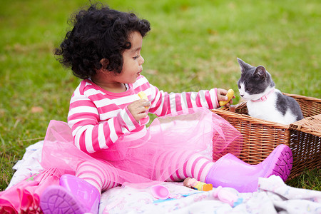 宠物图标简约黑白摄影照片_给你......可爱的小女孩在野餐时给她的宠物小猫提供一些食物。