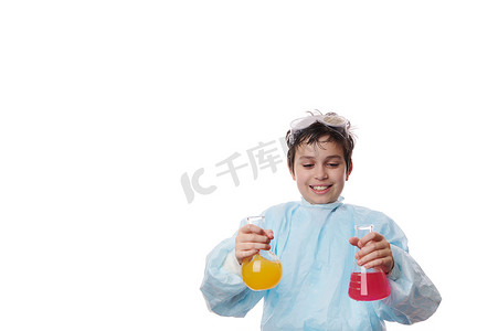 年轻的化学家 — 穿着实验室外套的聪明的青春期前男学生，在化学课上将化学试剂倒入玻璃瓶中。