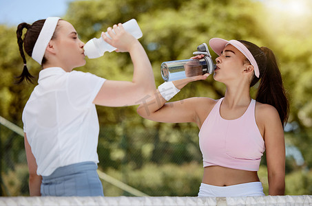 炎热摄影照片_网球、健身和水，比赛中炎热的夏日阳光下，女人们在球场上用瓶子喝水。