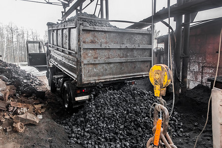 自卸车从工业区起重机起重机构旁边的焦煤车身卸载到垃圾填埋场