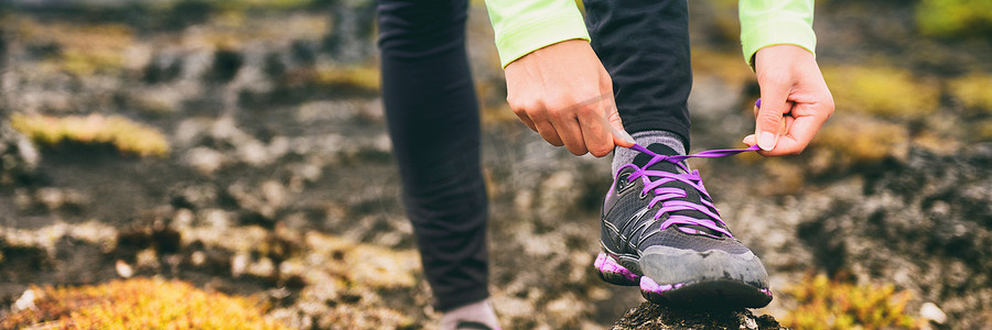 越野跑运动员女子系跑鞋鞋带，准备训练有氧运动。