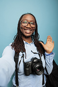 快乐自信的摄影爱好者在为个人频道录制视频博客视频时向相机挥手。