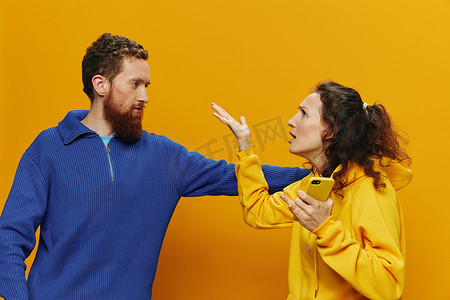 黄色背景中，手拿手机、社交网络和沟通的男女欢快夫妇微笑着，开心地打架。