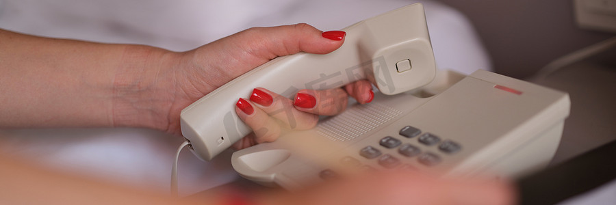 女人在酒店特写镜头中拿起电话并拨打客房服务号码