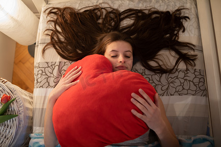 熟睡的女孩手里拿着一个红色的枕头。