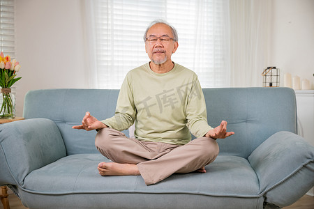 亚洲老人莲花坐闭眼练习瑜伽和冥想