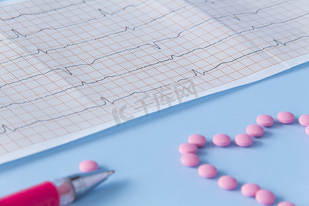 蓝色背景上的心电图上有一大把粉色药丸，呈心脏形状。