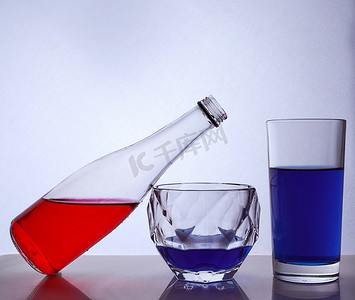 由瓶子和玻璃杯组成，白色背景上有多彩多姿的液体。