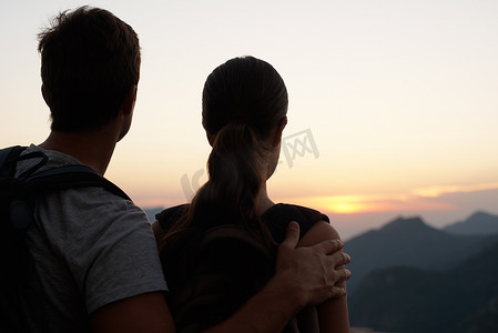 欣赏这一切的威严……一对年轻夫妇眺望日落的后视图。