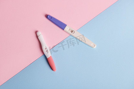 背景喷墨摄影照片_在蓝色粉红色背景下隔离的顶视图阳性喷墨妊娠测试。