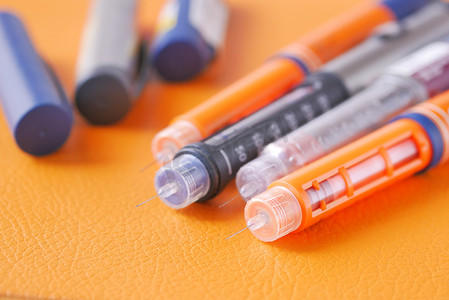 医务室背景摄影照片_橙色背景中的许多胰岛素笔