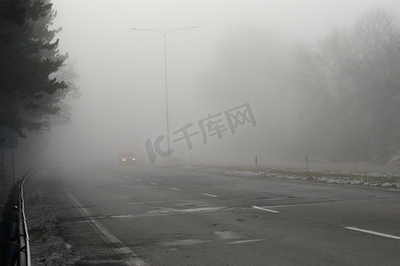 汽车在雾蒙蒙的道路上行驶时，头灯或头灯都亮着。