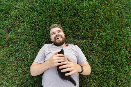有小猫的男人躺在草地上玩耍 — 友谊爱动物和宠物主人的概念