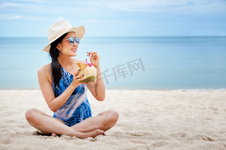 海滩上喝新鲜椰子水的快乐女人