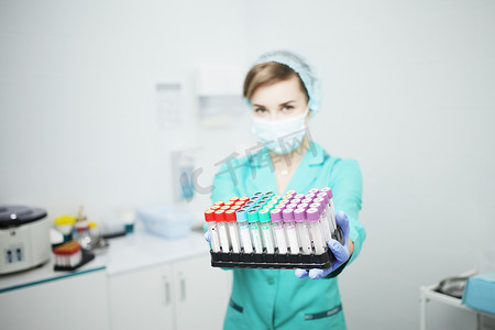 阻止冠状病毒摄影照片_一位戴着医用口罩的女护士医生拿着试管进行血液检查