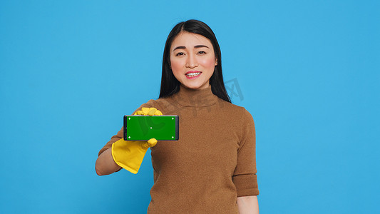 亚洲女佣在与远程客户交谈时拿着色度键模拟带绿屏显示的智能手机