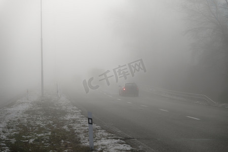 汽车在雾蒙蒙的道路上行驶时，头灯或头灯都亮着。