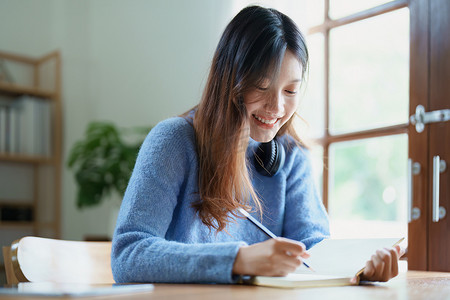 一位亚洲少女在家里的木桌上使用笔记本通过视频会议在线学习的肖像