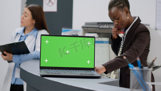 医院接待柜台上有绿屏模板的笔记本电脑