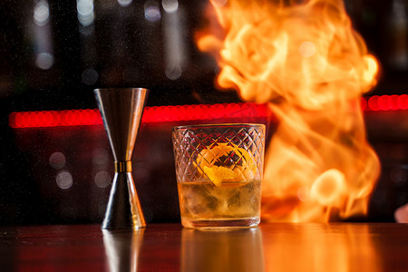 调酒师用橙皮特写在鸡尾酒上点燃火焰