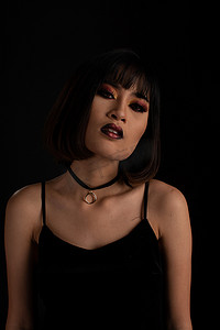 东南亚人摄影照片_黑色背景中深色调妆容的东南亚女性
