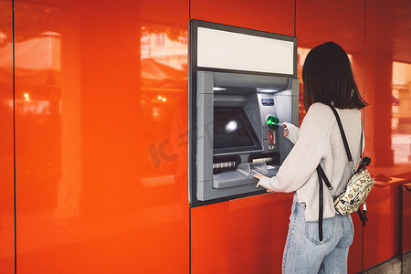 妇女将卡插入 ATM 机提取现金