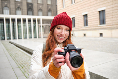 美丽的读头女孩，带专业相机的摄影师在户外拍照，在城市里散步拍照，观光