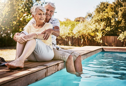 年长夫妇在泳池边拥抱和放松，享受爱情和暑假，在户外增进感情或共度美好时光。