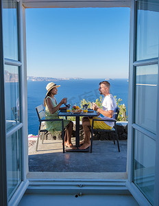 夫妇在希腊圣托里尼岛度假，男人和女人在传统的圆顶屋里吃早餐