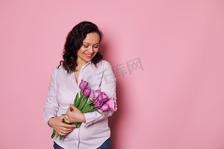 美丽的年轻孕妇感到快乐，收到一束紫色郁金香。