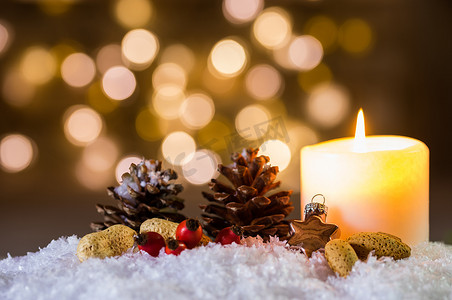 雪上燃烧的蜡烛和圣诞装饰，灯光背景模糊，充满节日气氛
