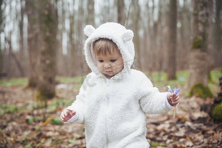 森林里一棵倒下的树旁穿着熊服装的可爱婴儿